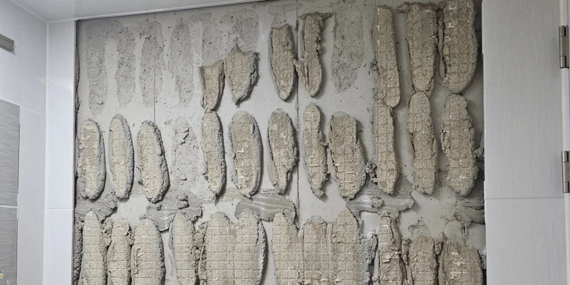 욕실 벽타일 교체를 위해 기존 타일을 떼어내 접착제 자국이 드러난 큰 벽면